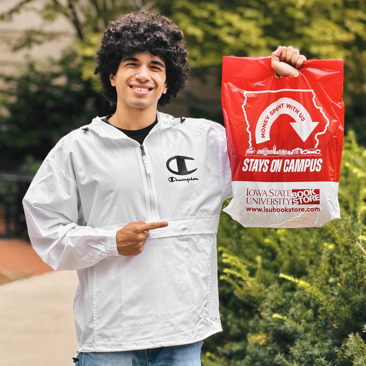 A Cyclone wearing the Champion White packable jacket and holding an ISU Book Store Bag